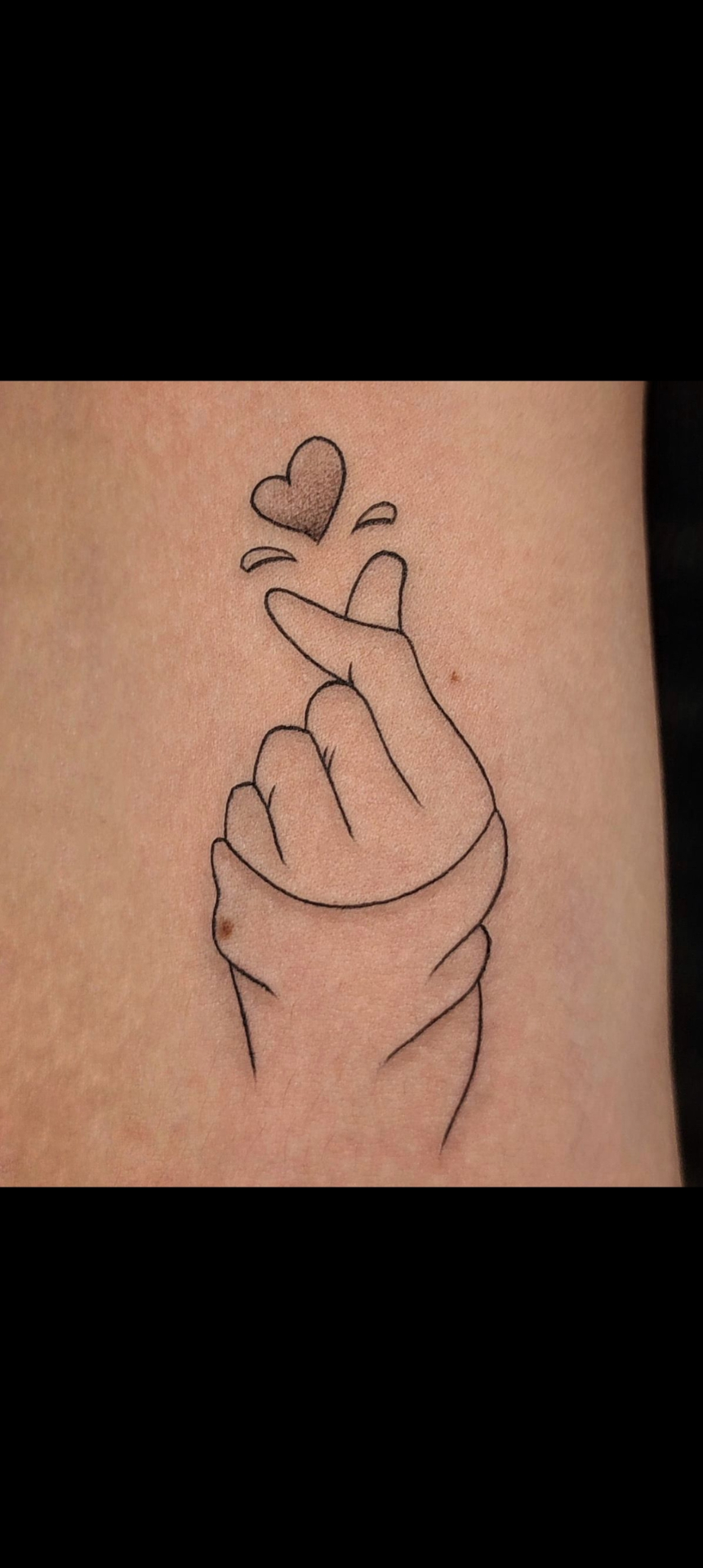 Tatuaje de mano haciendo corazón coreano en línea fina — tatuajes línea fina Madrid · As de Picas Madrid