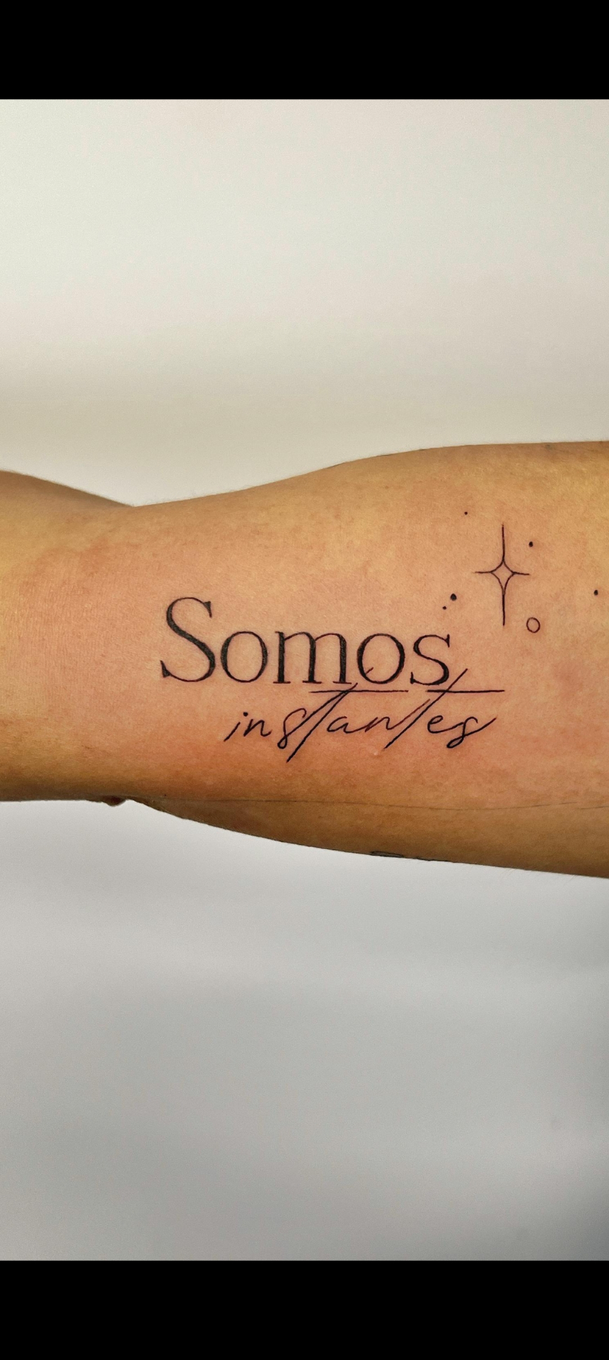 Tatuaje de lettering fino 'Somos instantes' con estrellas — estilo línea fina en Madrid centro · As de Picas Madrid