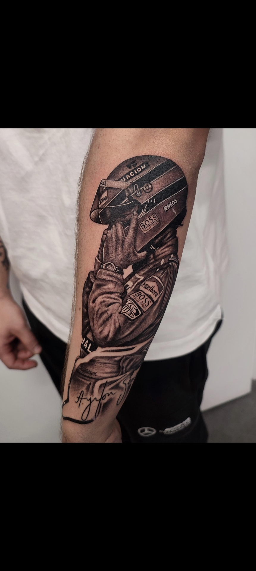 Tatuaje realista de Ayrton Senna con casco y mono de F1 — estilo realismo negro y gris en Madrid centro · As de Picas Madrid